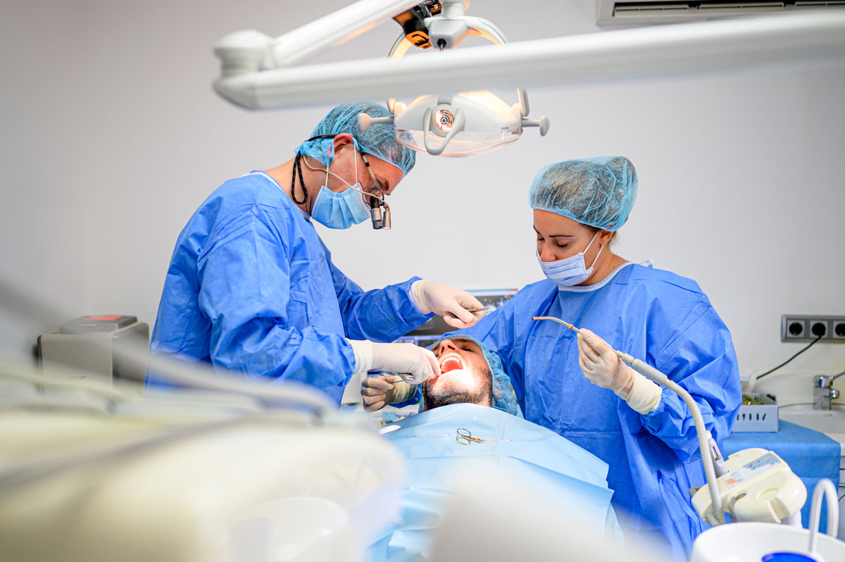 medic dentist si asistent in timpul unei interventii stomatologice